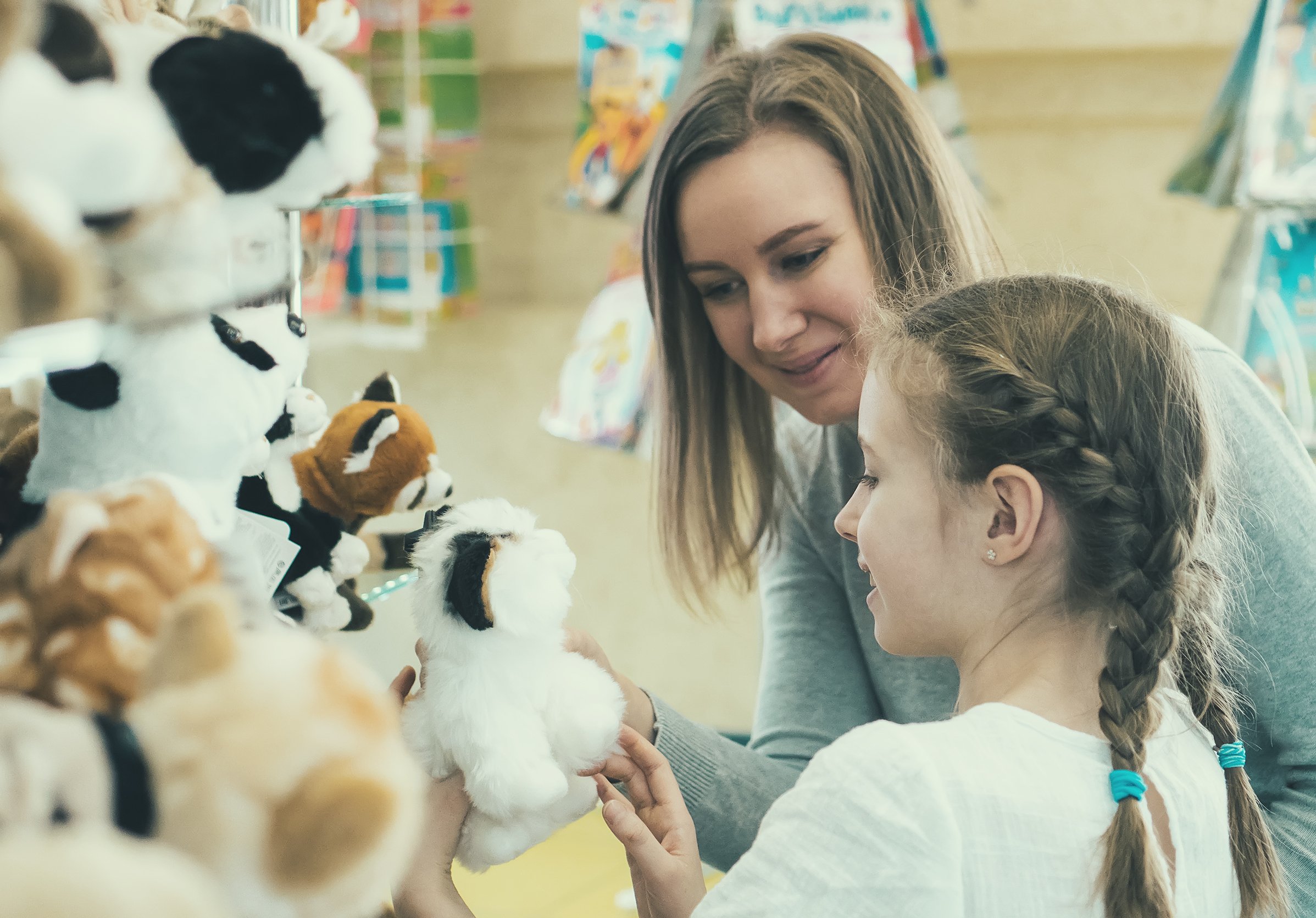 A woman and a young girl looking at toys.