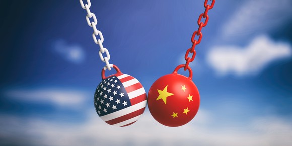 Two wrecking balls, adorned with American and Chinese flags, colliding in midair.