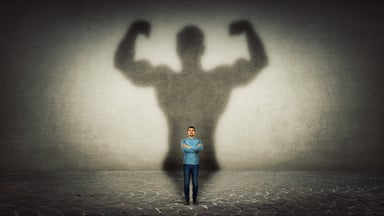 A mans muscular shadow on a wall.