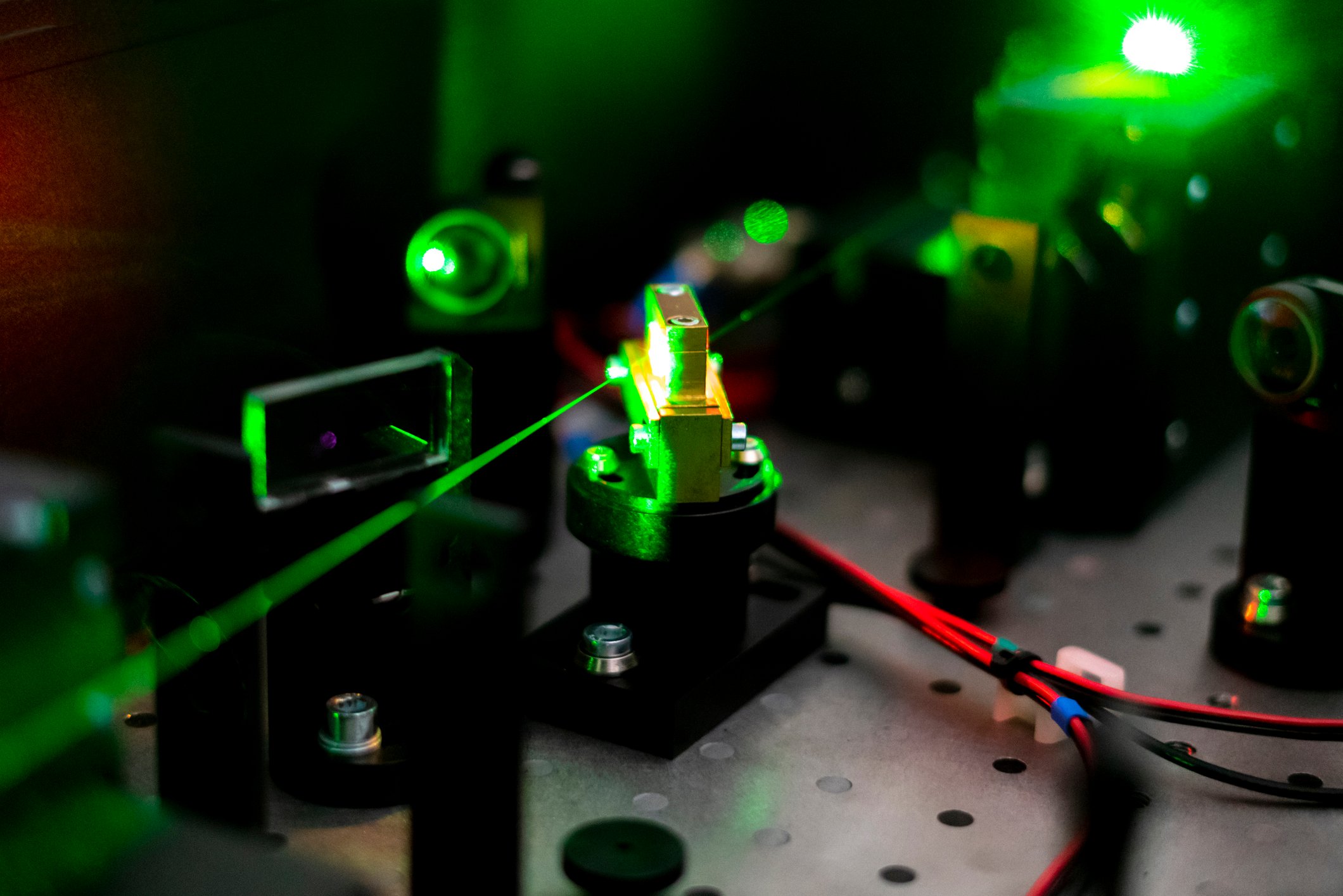 A green laser beam shines through an array of electronic circuits