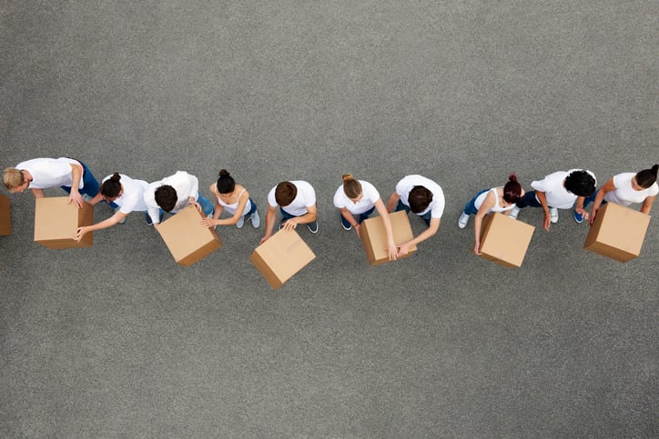 A line of individuals passing cardboard boxes from one end to the other.