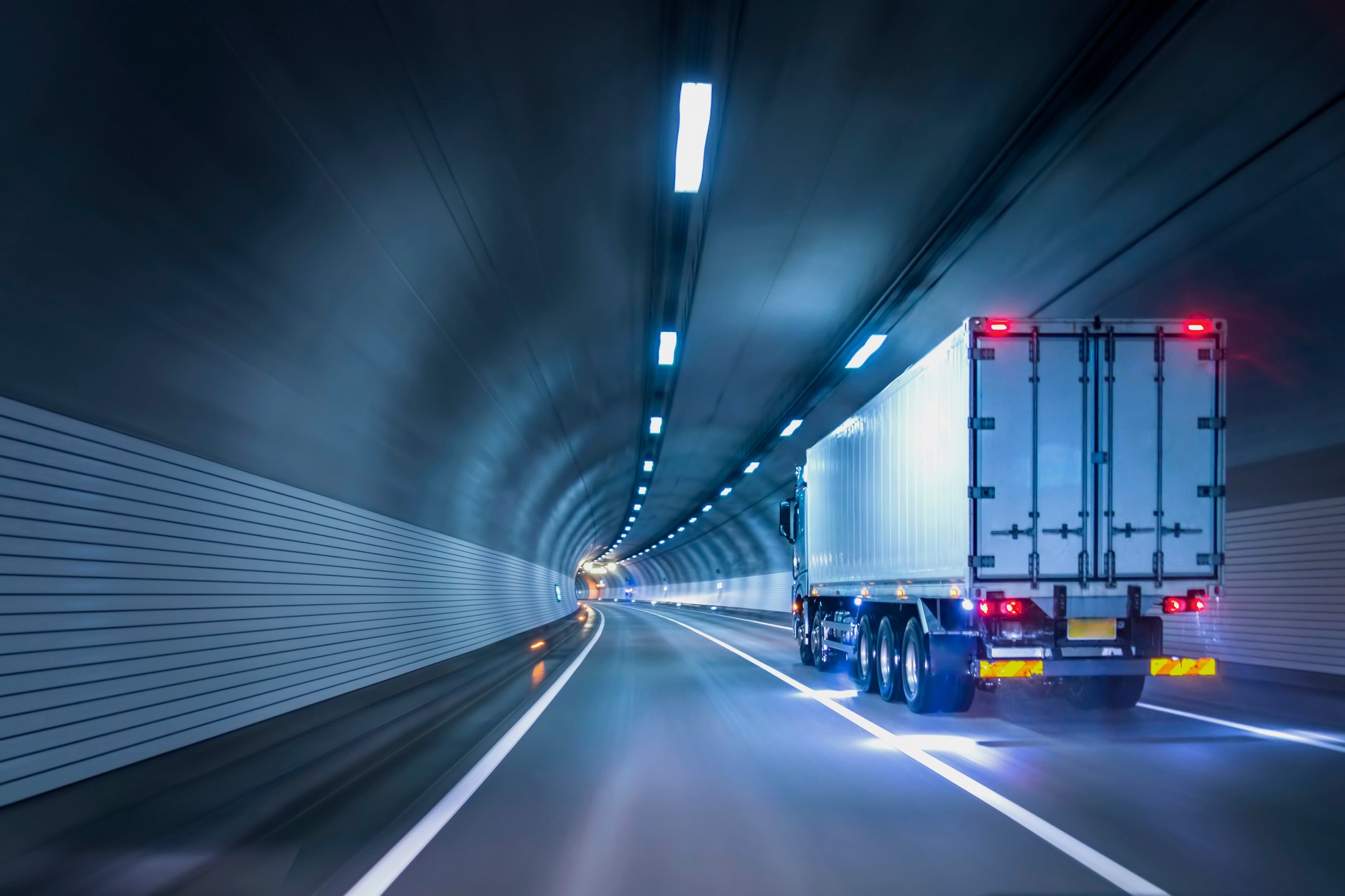 A truck driving in a lit-up highway tunnel