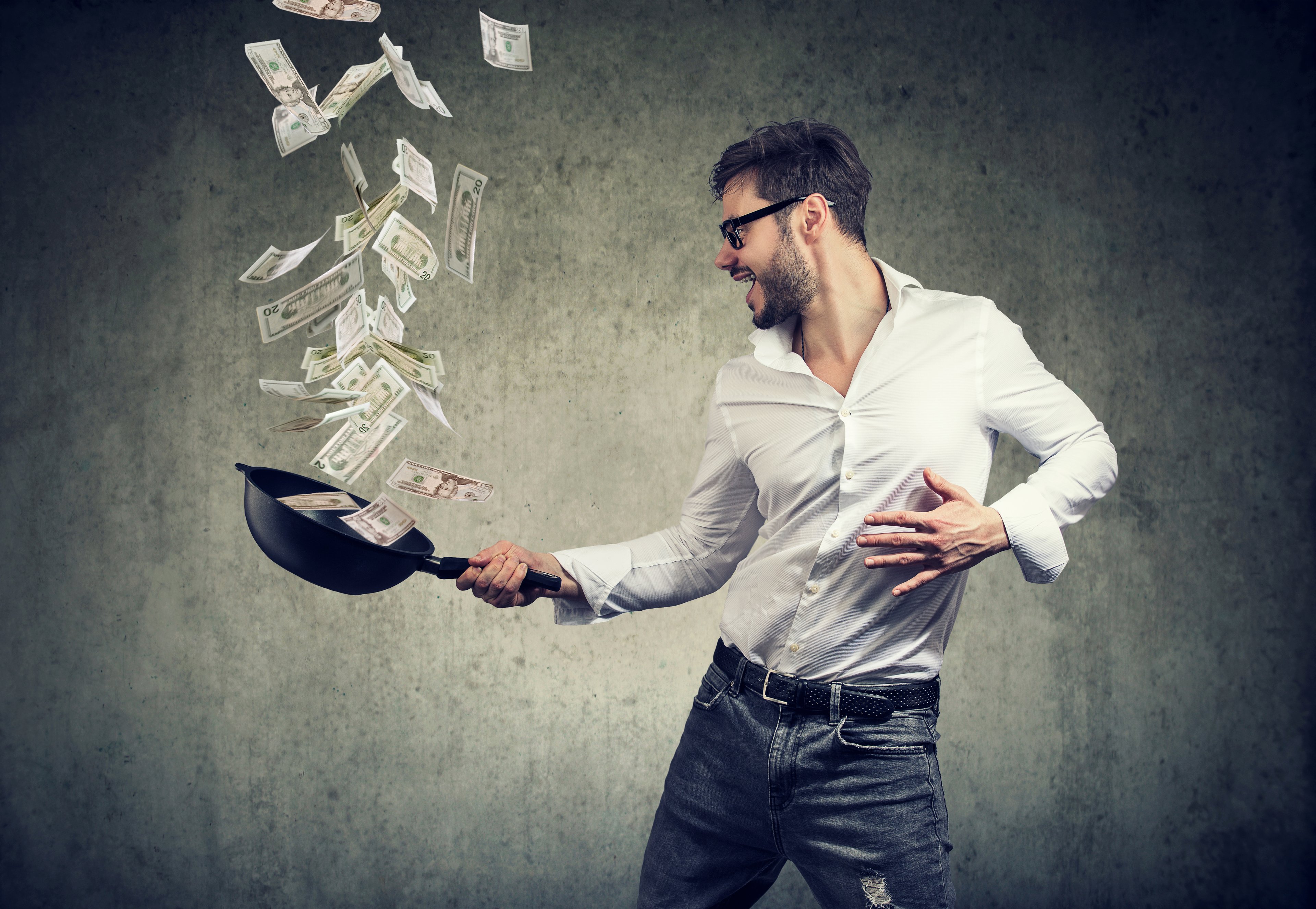 Man tossing cash in a skillet.