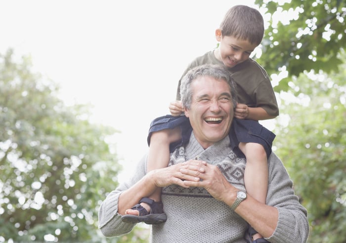 A grandfather holding his grandson on his shoulders