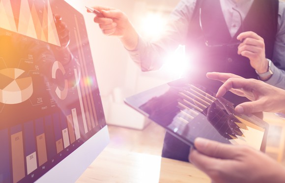 People discussing financial charts on screens.