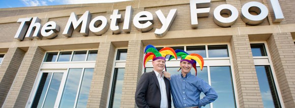 Tom and David Gardner, wearing jester caps, and standing in front of The Motley Fool HQ.