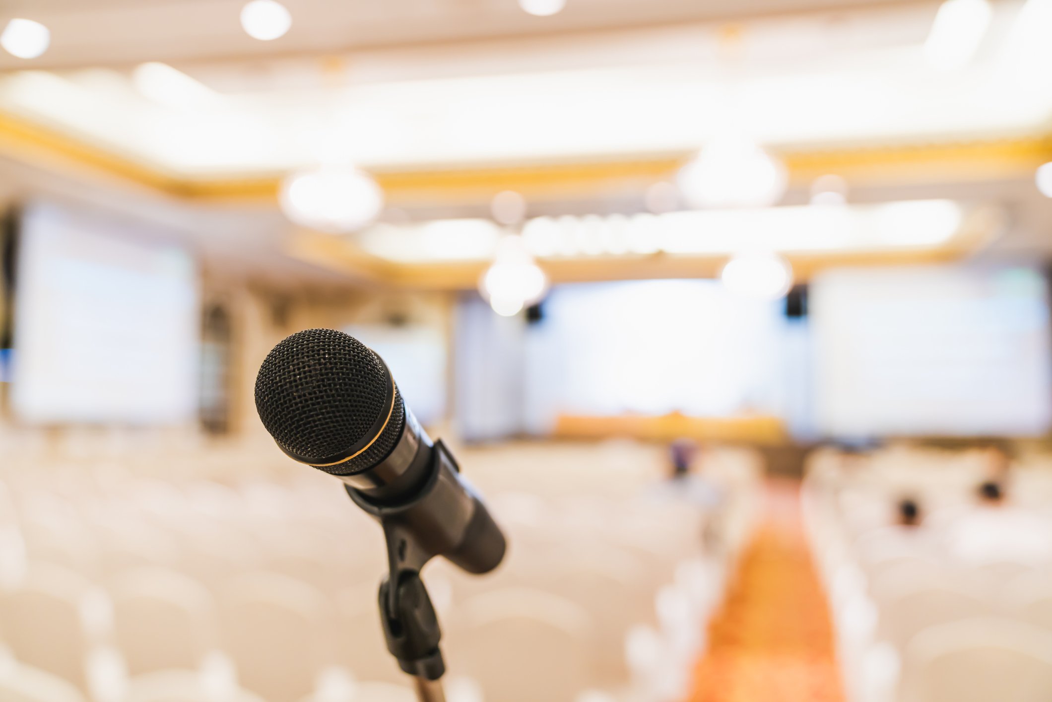 A microphone on a stand in front of an empty conference room.