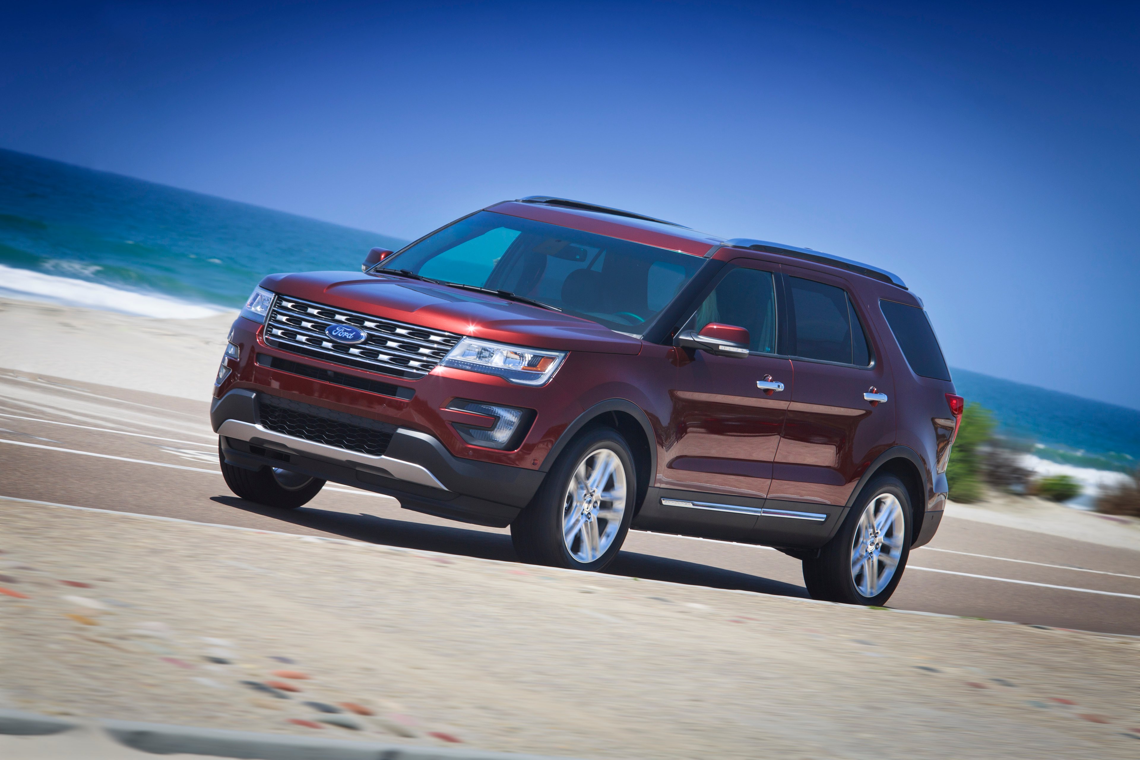 A dark red 2016 Ford Explorer, a midsize SUV, on a beach road. 