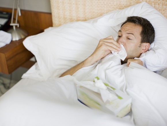 Man lying in bed, wiping his nose