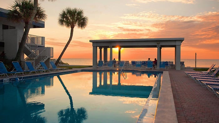 A beachside hotel pool reflecting a sunset