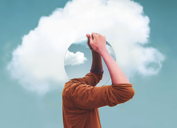 A person holding a reflective sphere where their head should be with a cloud in the background.