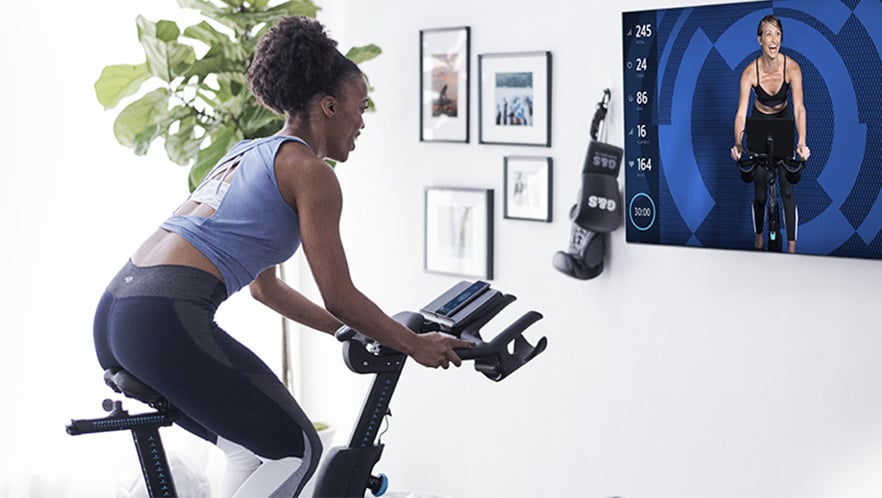 A woman rides a connected exercise bike.