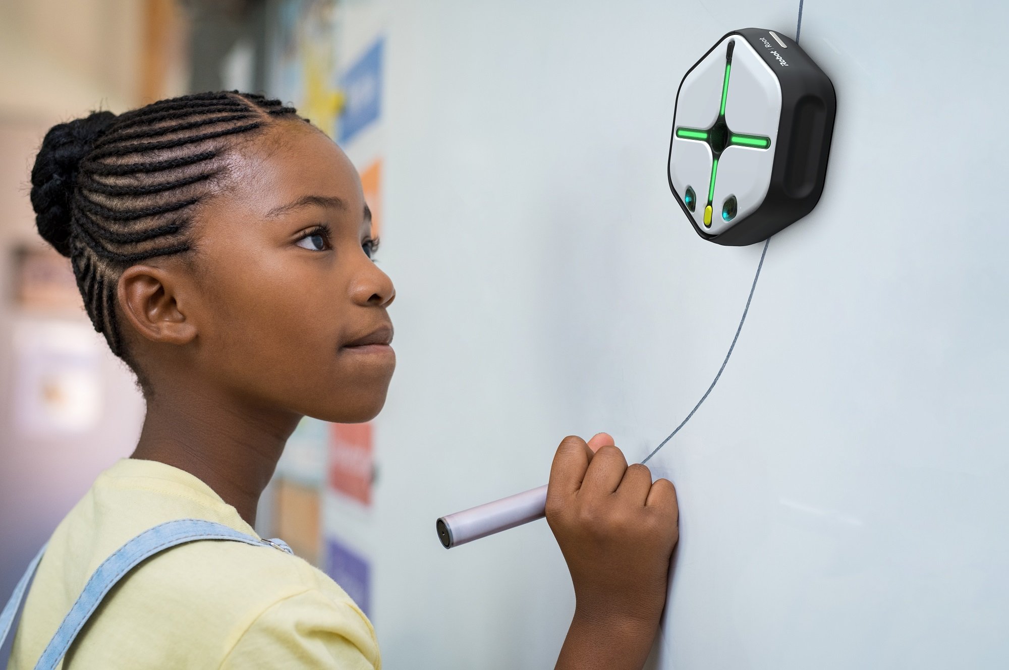 Young female student drawing a line for iRobot's Root coding robot to follow on a whiteboard.
