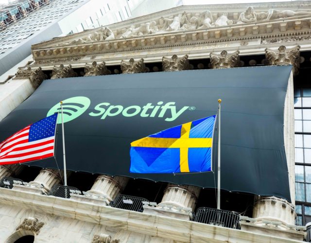 Spotify banner on the NYSE building; American and Swedish flags are in front.