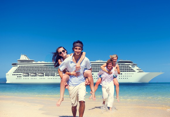 Two men and two women on a beach, with a cruise ship behind them.