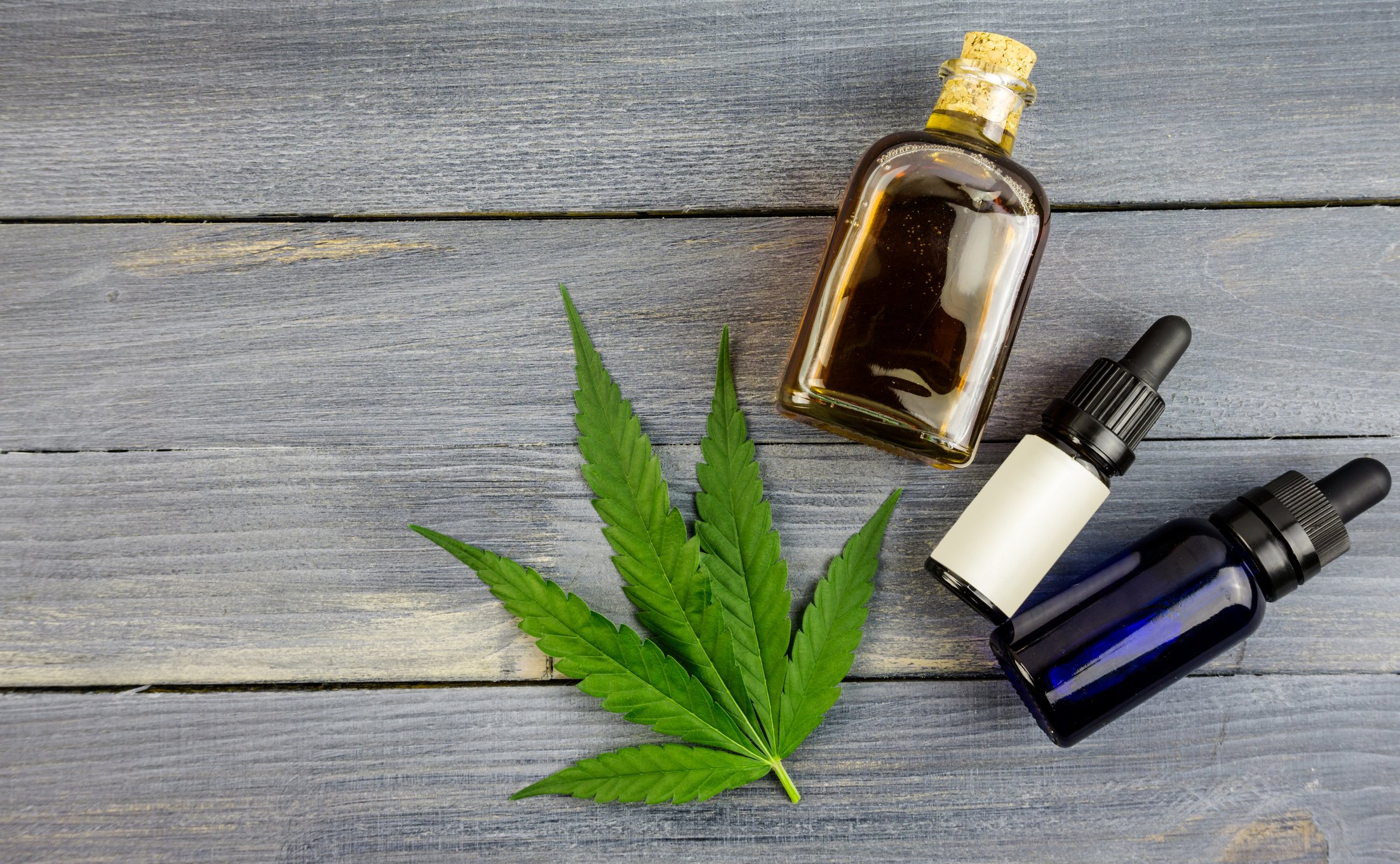 Marijuana leaf next to extract bottles
