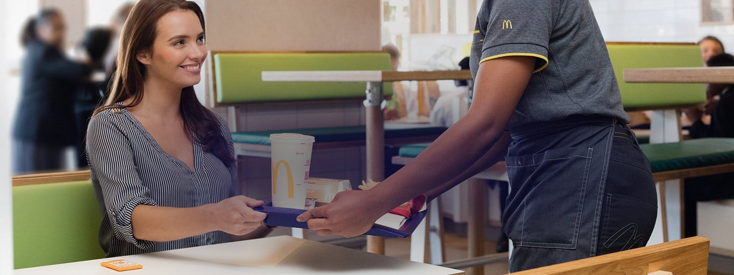 McDonald's employee bringing an order to a woman at a table