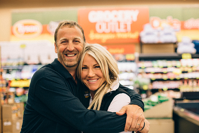 A man and a woman hugging inside a Grocery Outlet store.