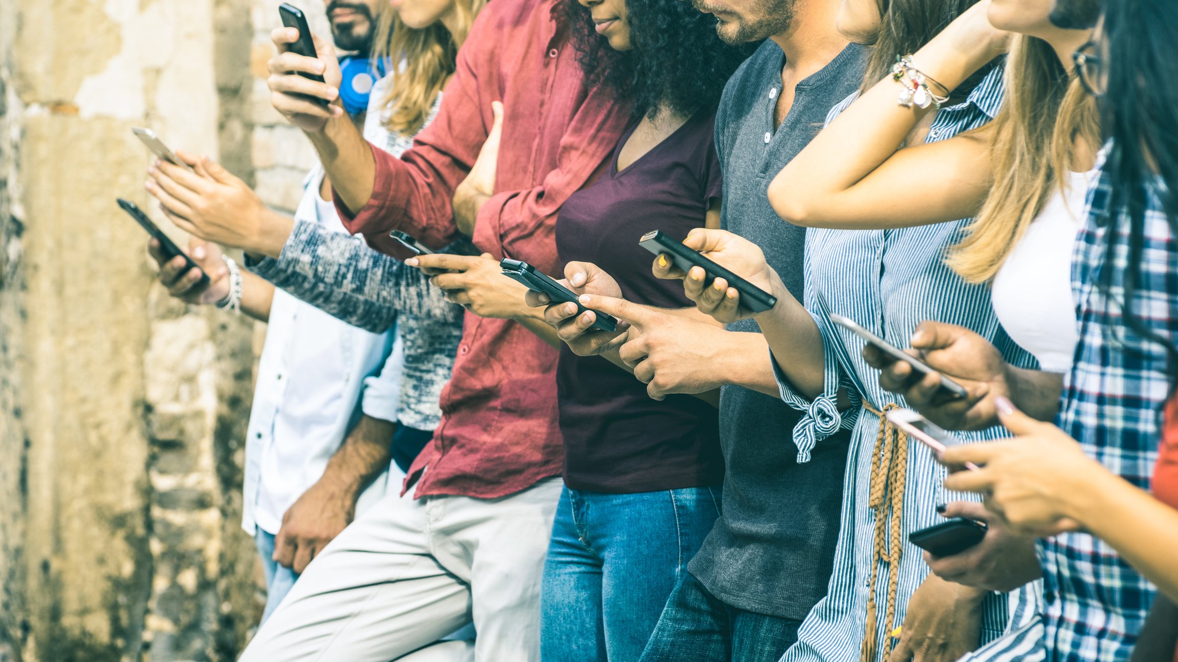 A line of young people looking at their phones. 