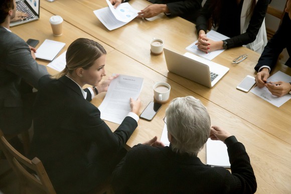 People in suits sitting around a conference table.