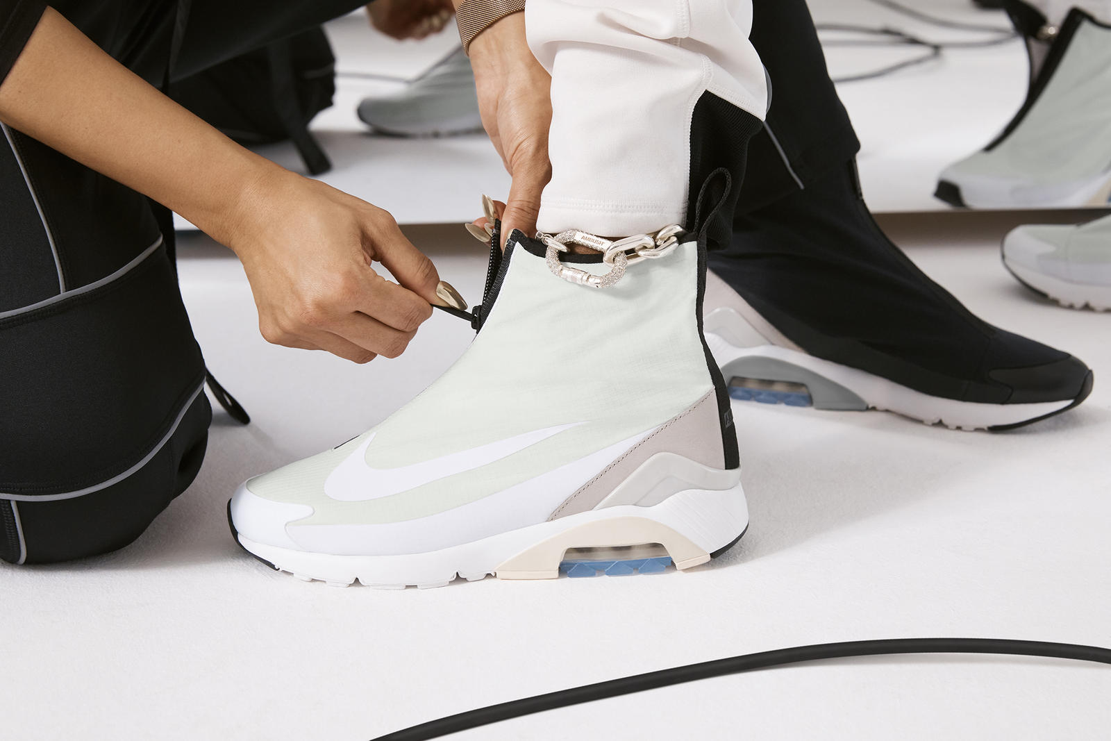 A person fitting a fashionable-looking Nike high-top sneaker on another person's foot.