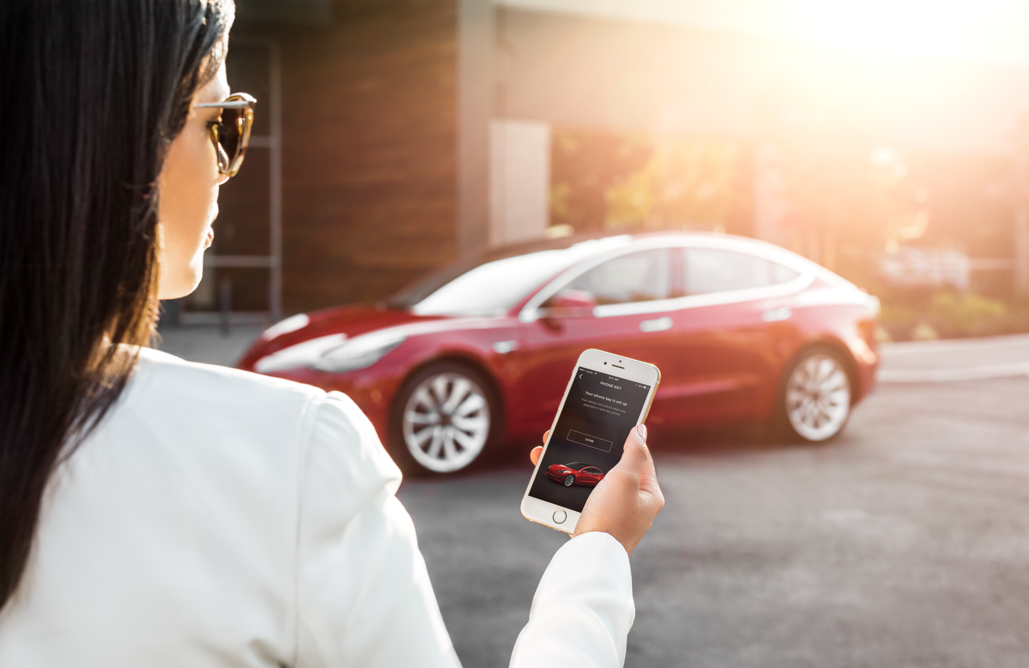 A woman unlocking her Model 3 with a Tesla app on her smartphone