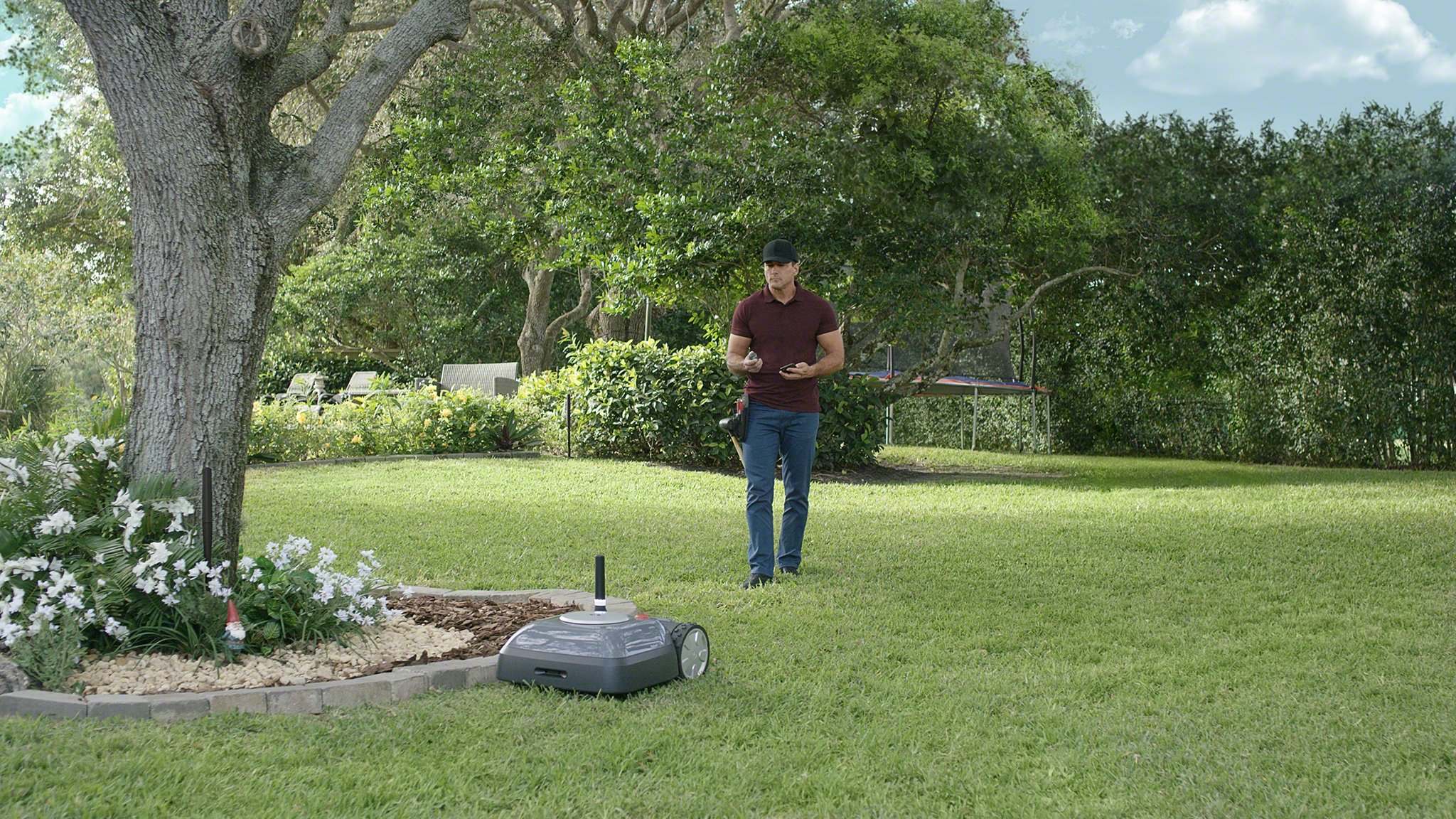 Man watching his iRobot Terra mower in the yard.