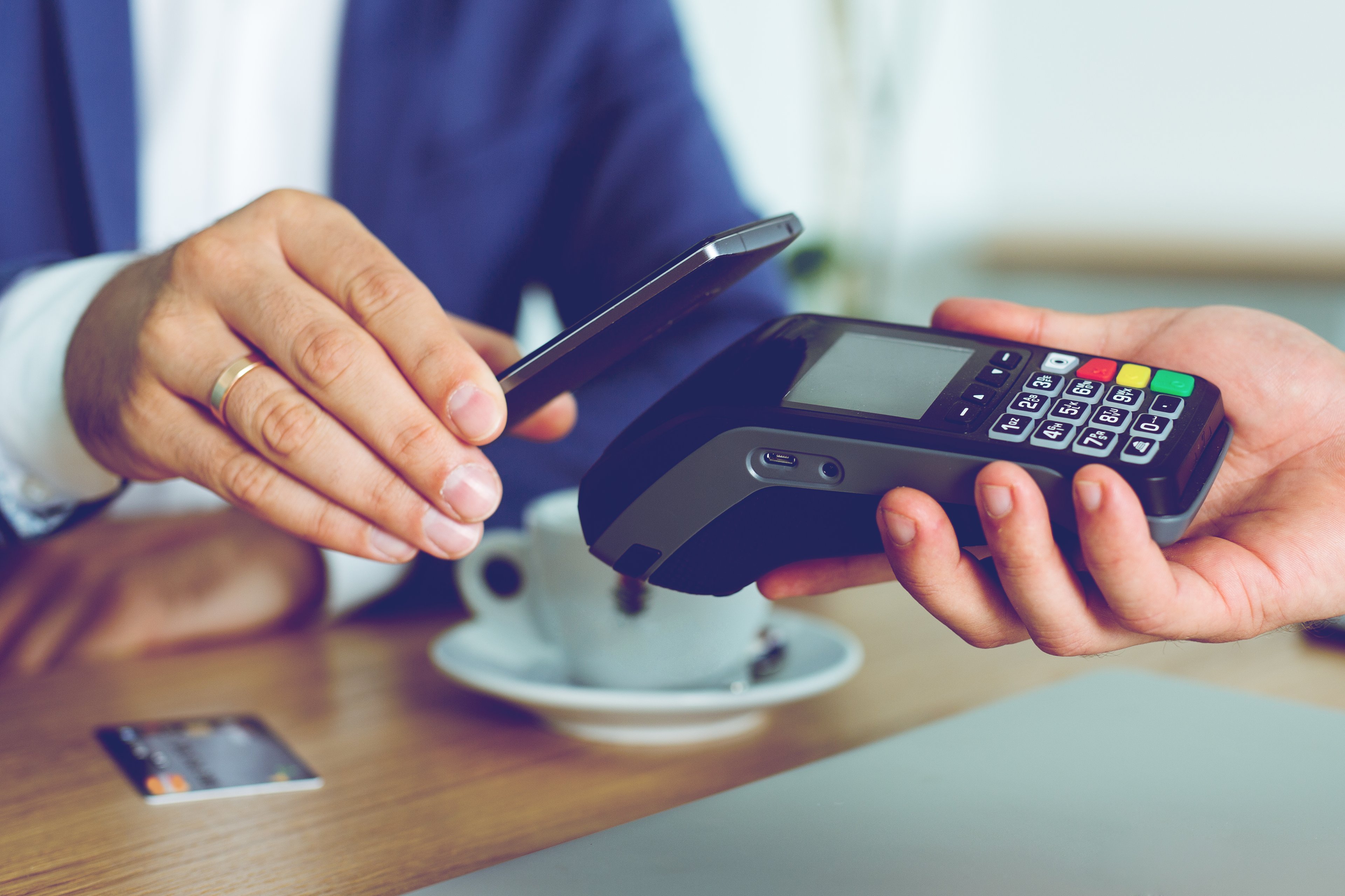 A customer in a cafe makes a cashless payment with a smartphone.