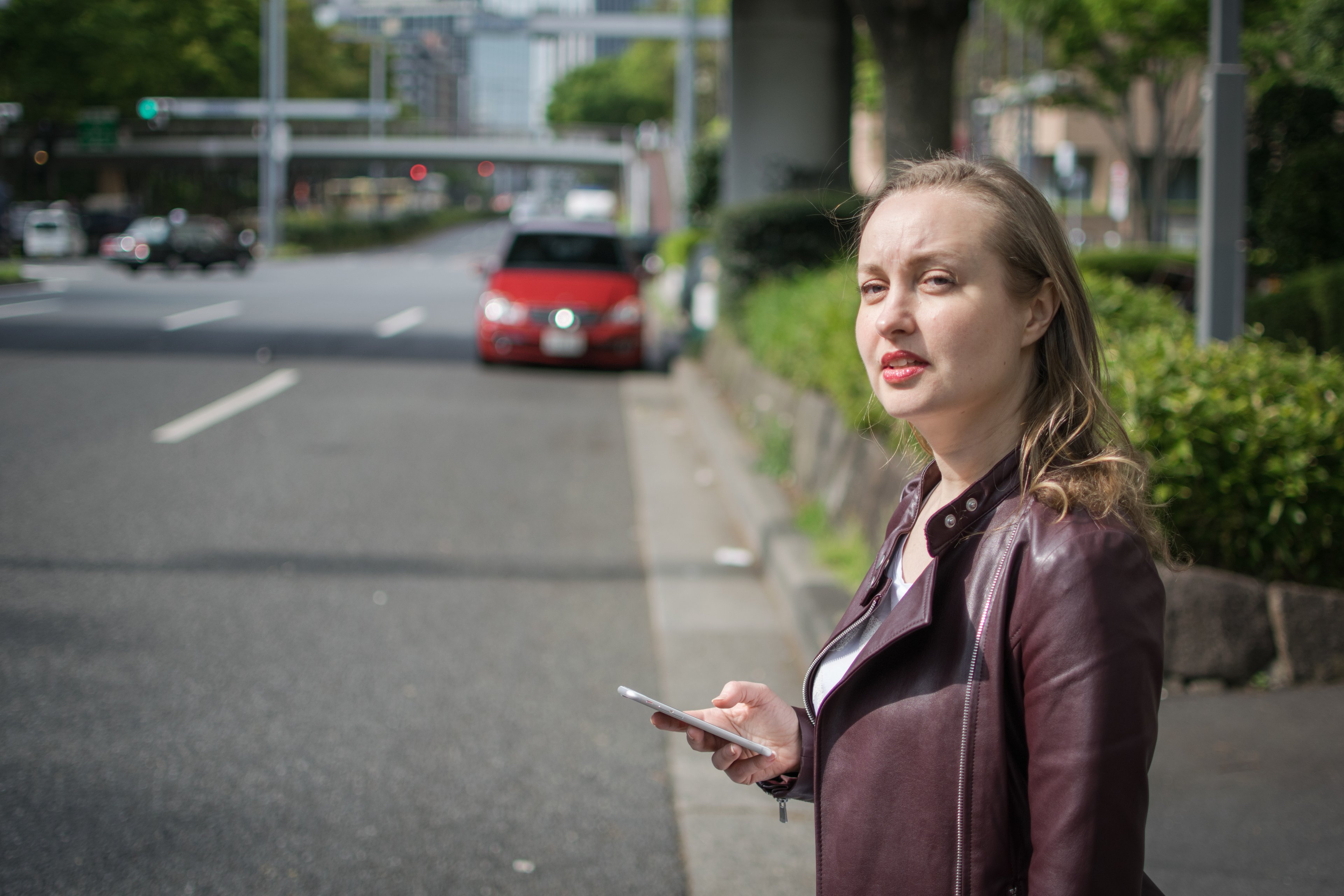 A young woman hails a ride using a smartphone.