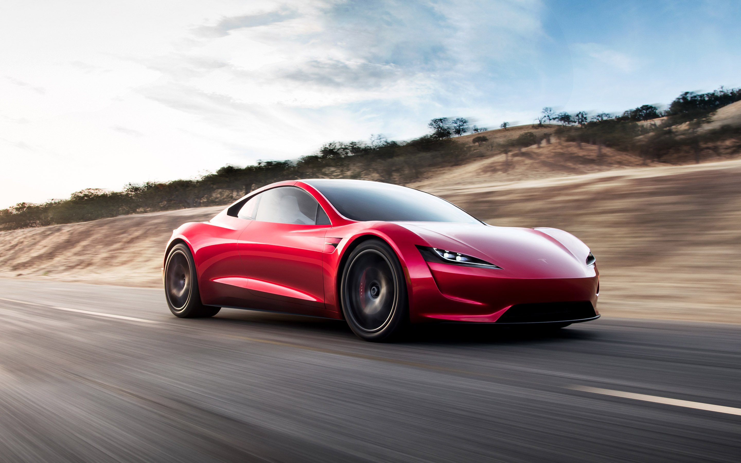 Red Tesla roadster in motion.
