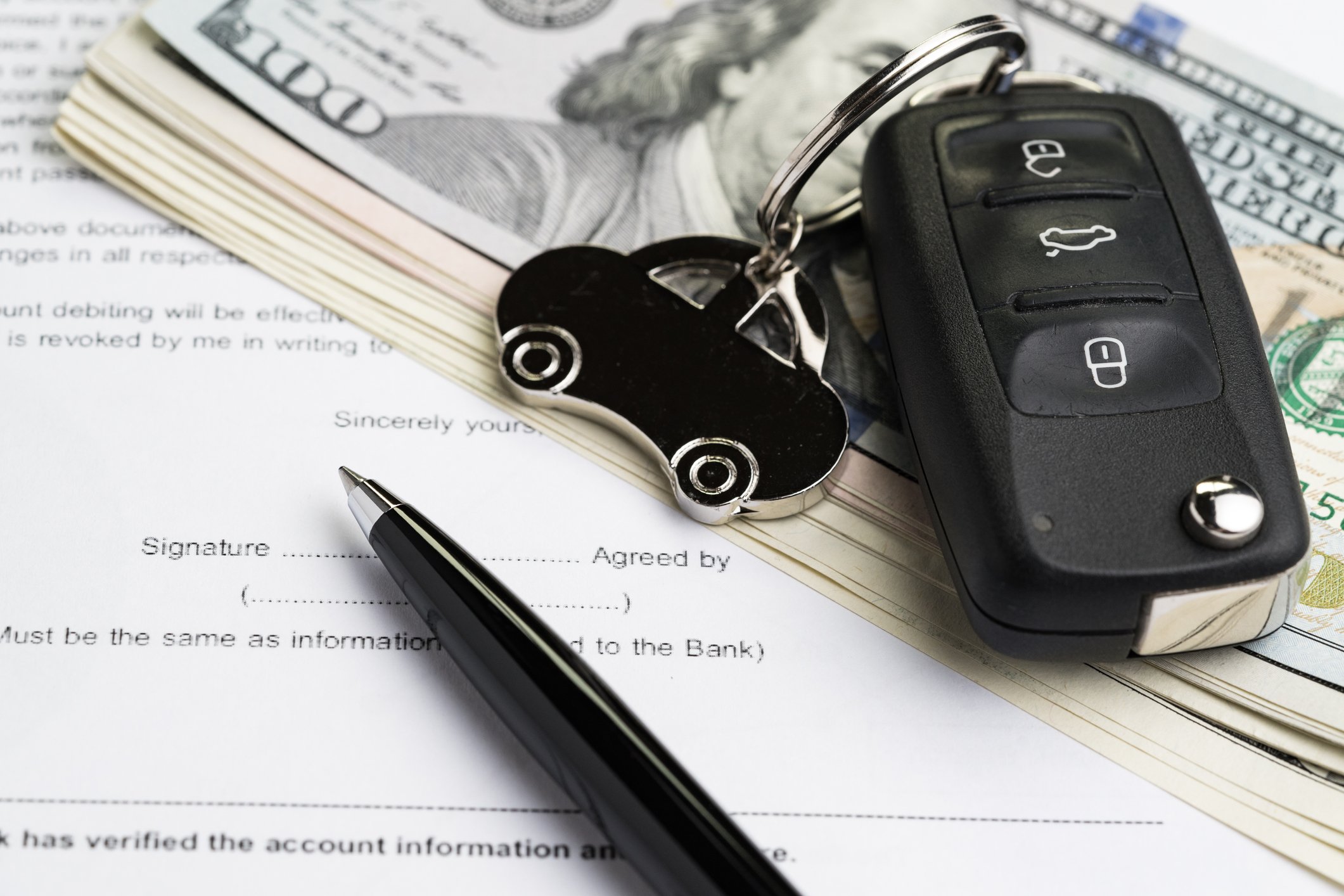 A car-buying agreement, a pen, and a car keychain.