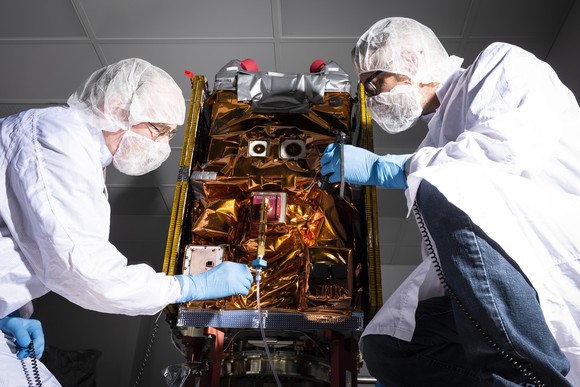 Two engineers working on a small satellite