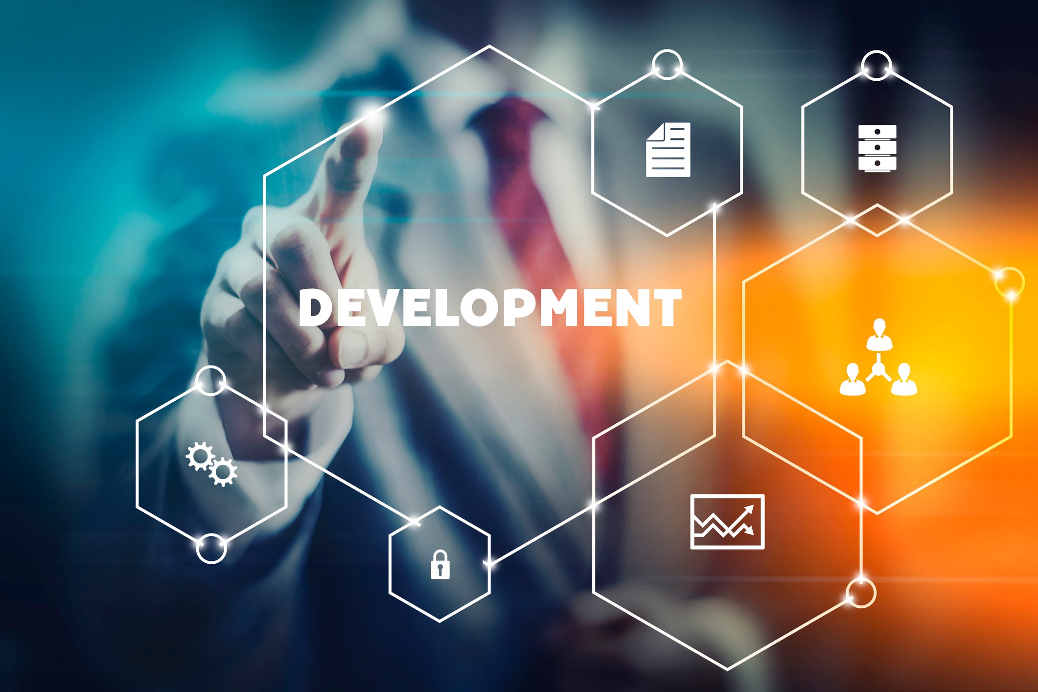 A man in a suit clicking a transparent screen with different icons with the word "development" emblazoned in the middle.