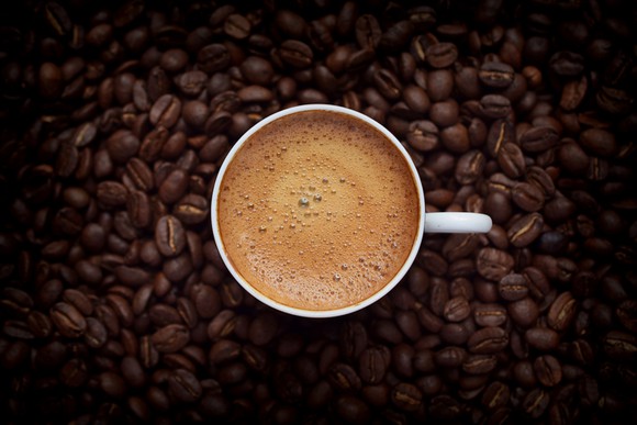 A coffee mug sitting on a mound of coffee beans.