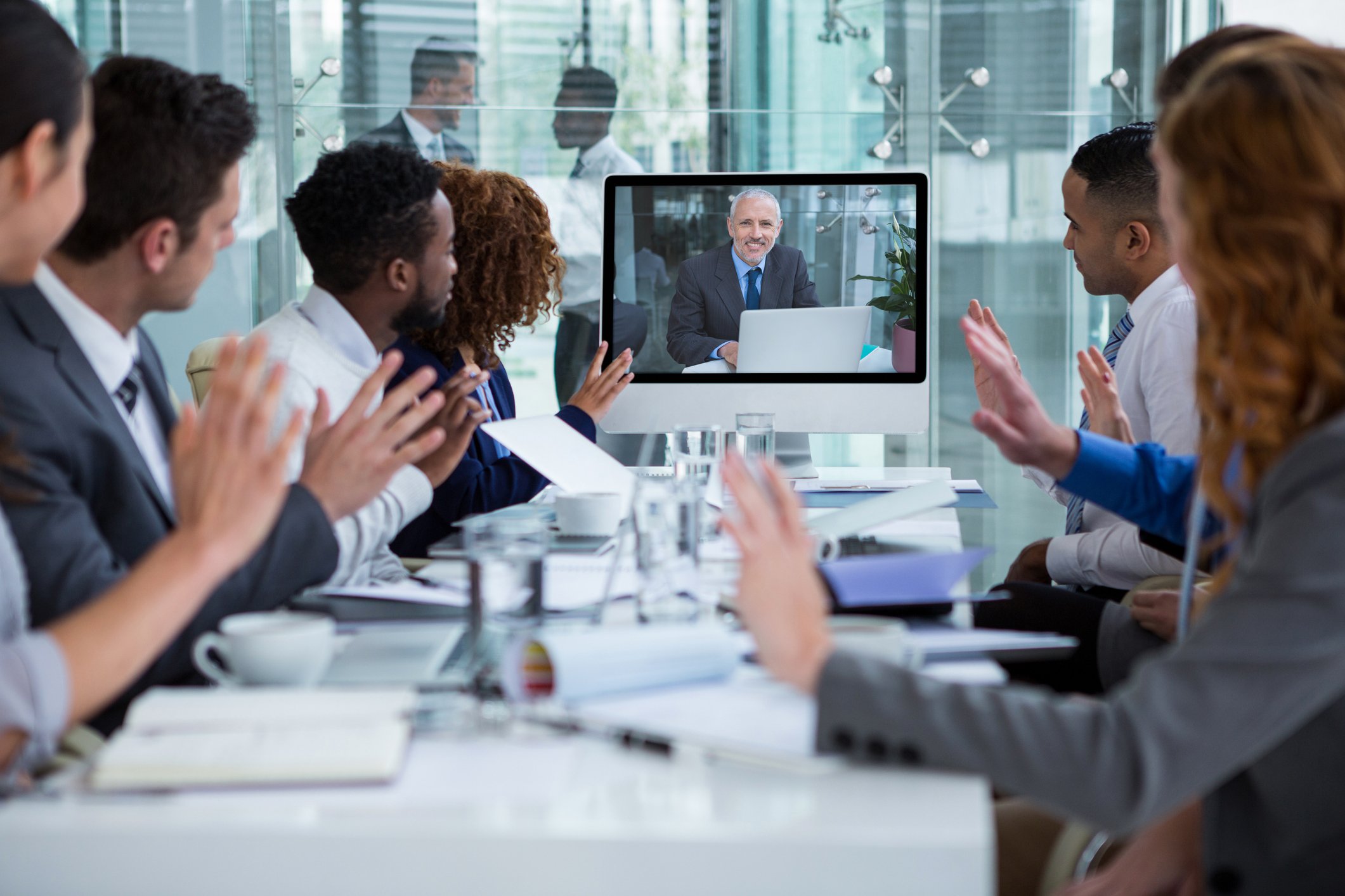 A group of people in an office watching a video monitor. 