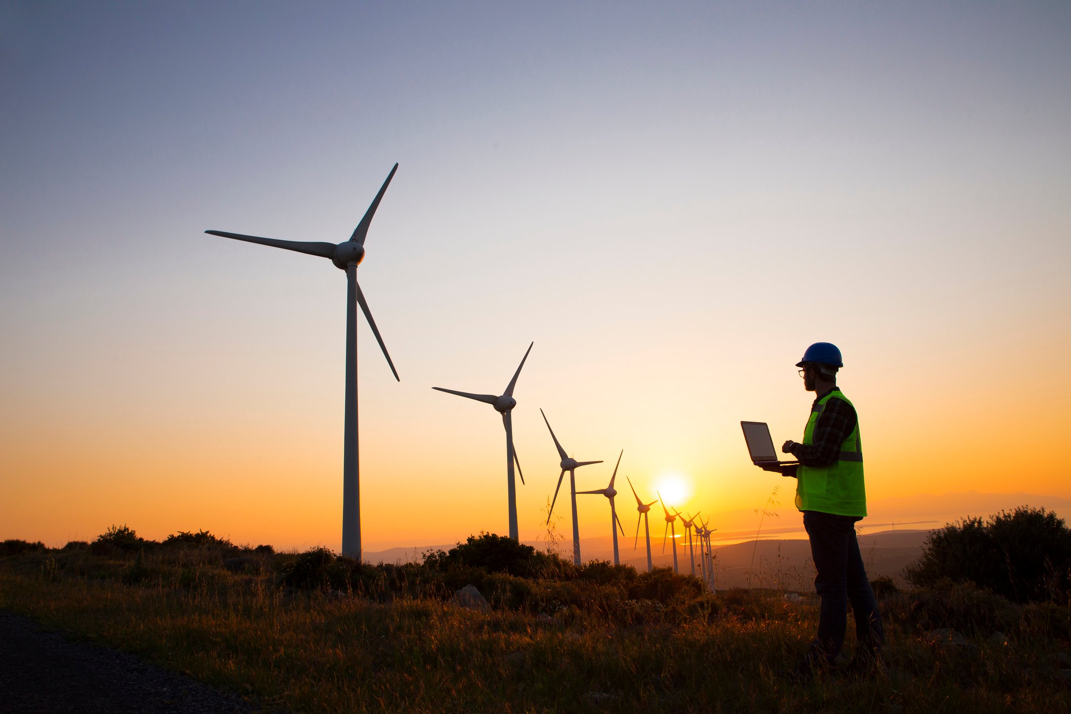 A person with a laptop inspecting wind turbines.