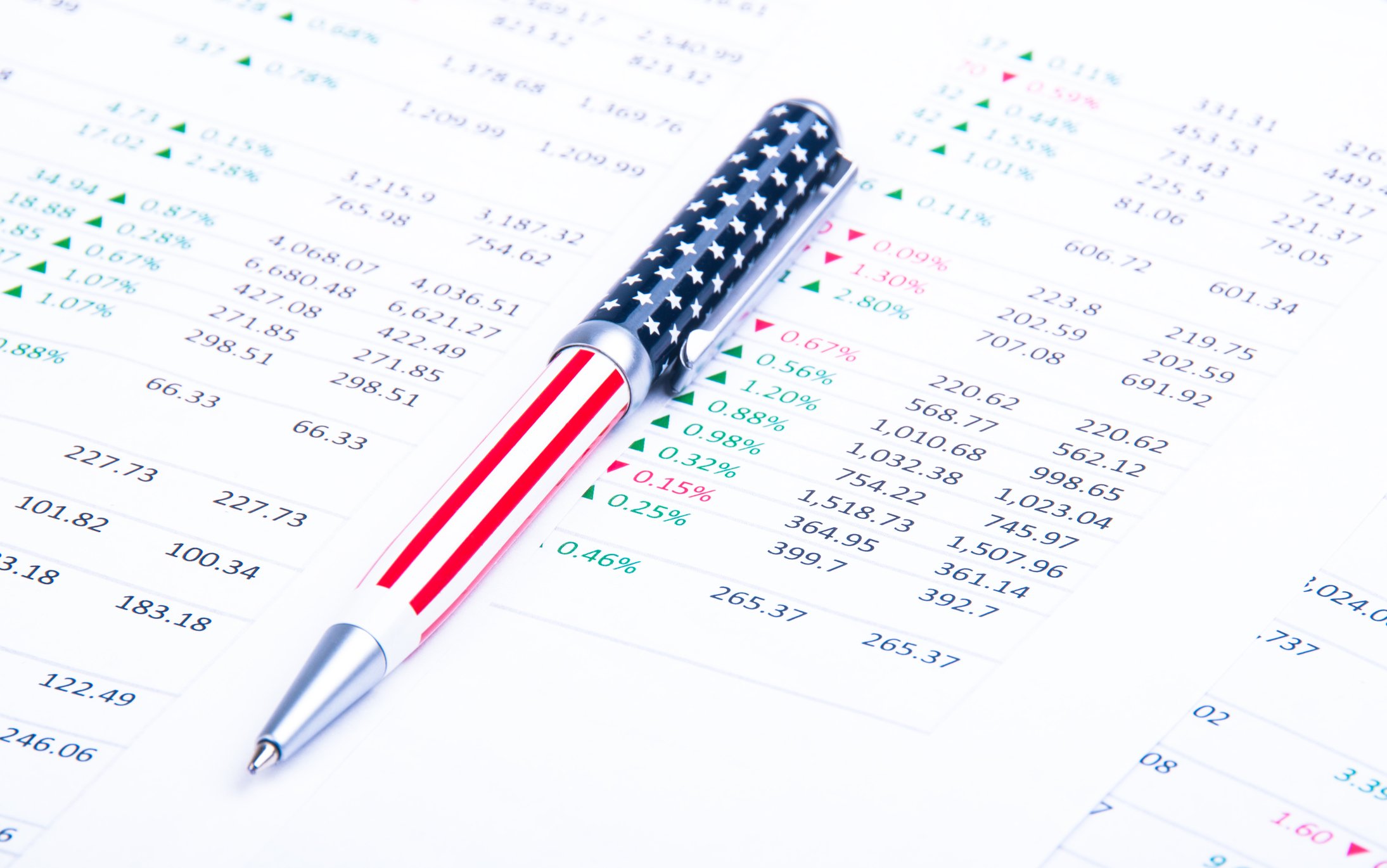 An American flag-themed pen lying atop a printout of financial data. 