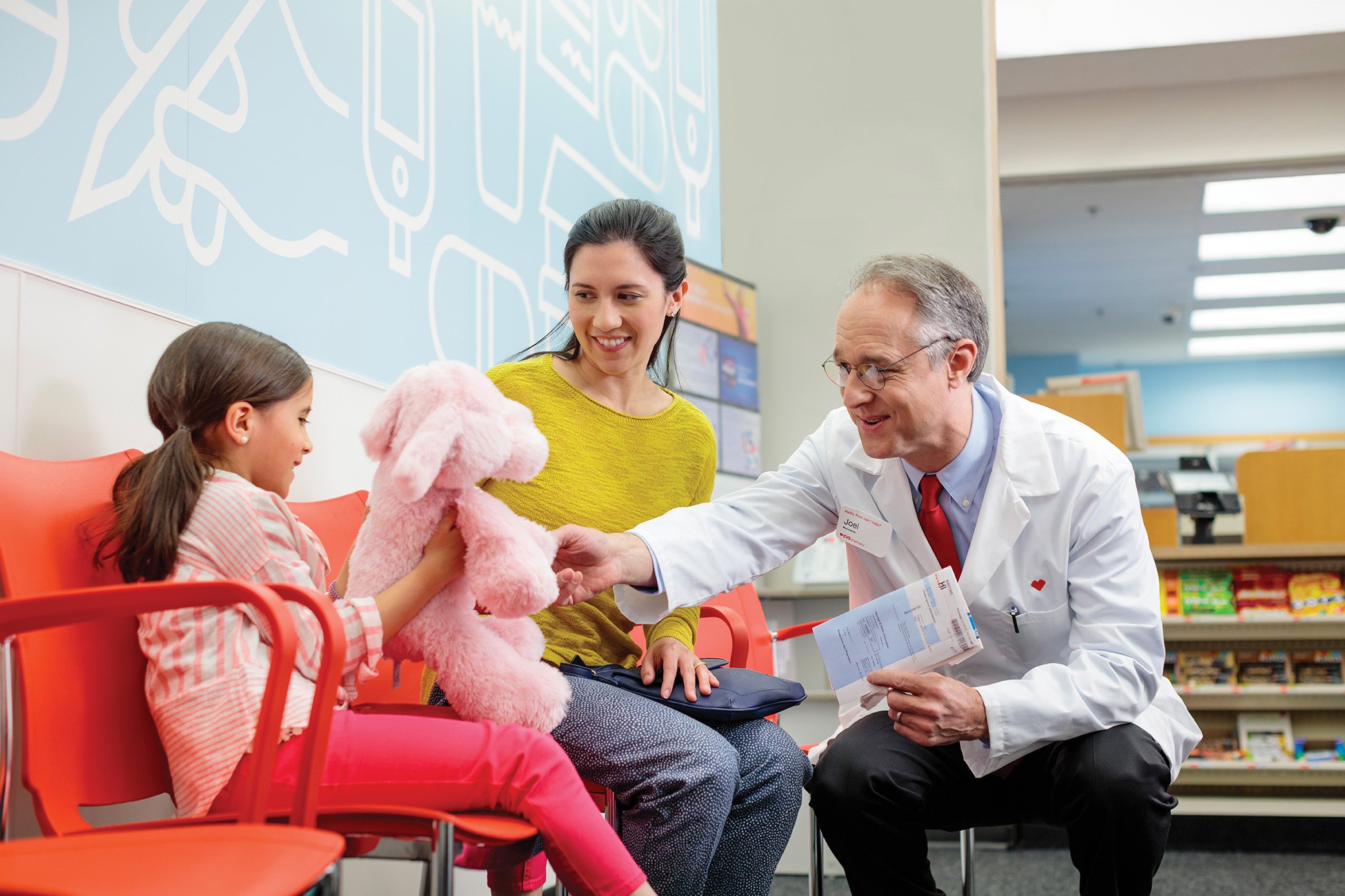 A CVS pharmacist touching a child's stuffed animal.