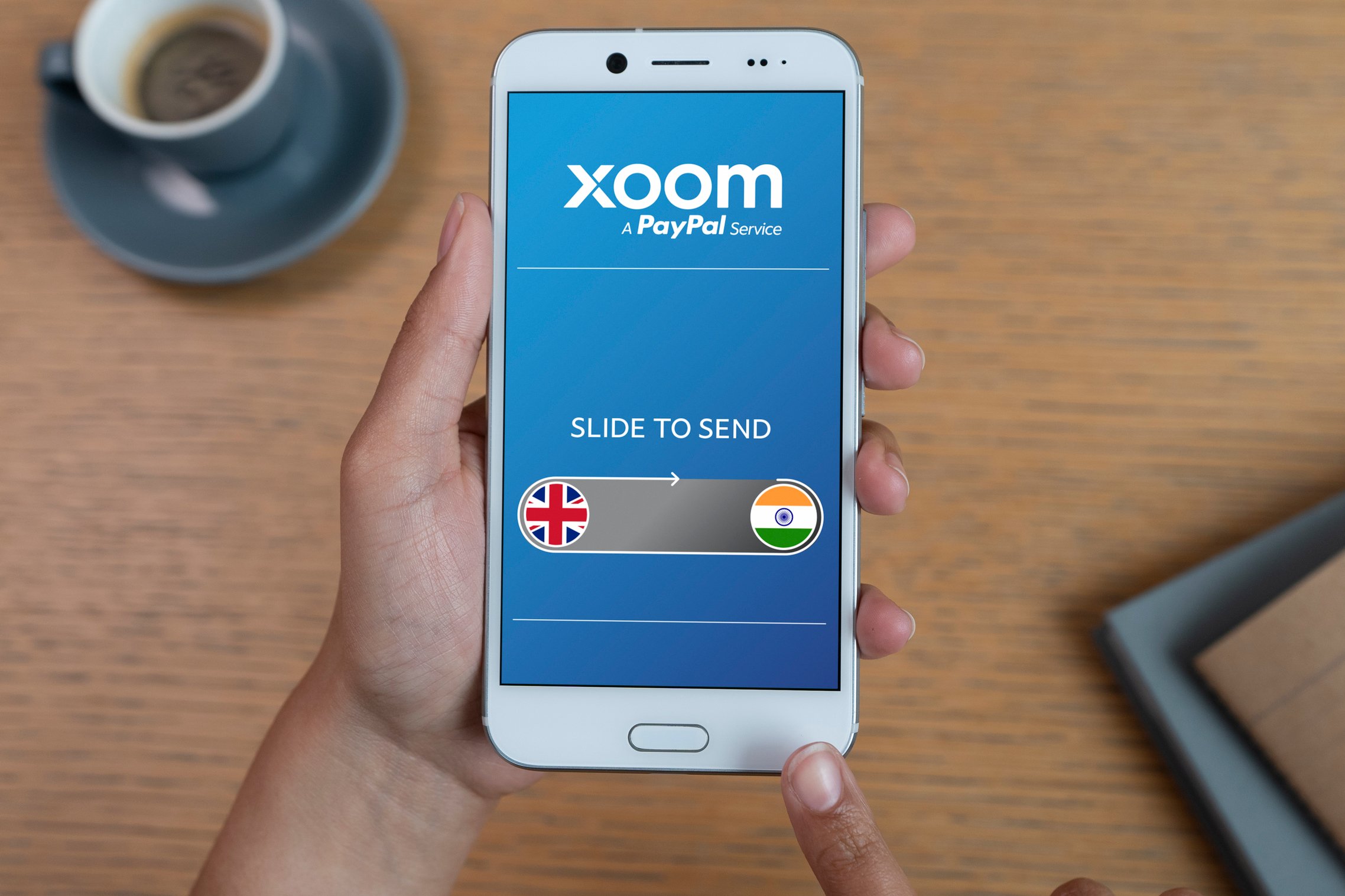 A man holding a smartphone featuring the Xoom app. 