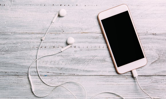Phone sitting on a table with earbuds next to it.