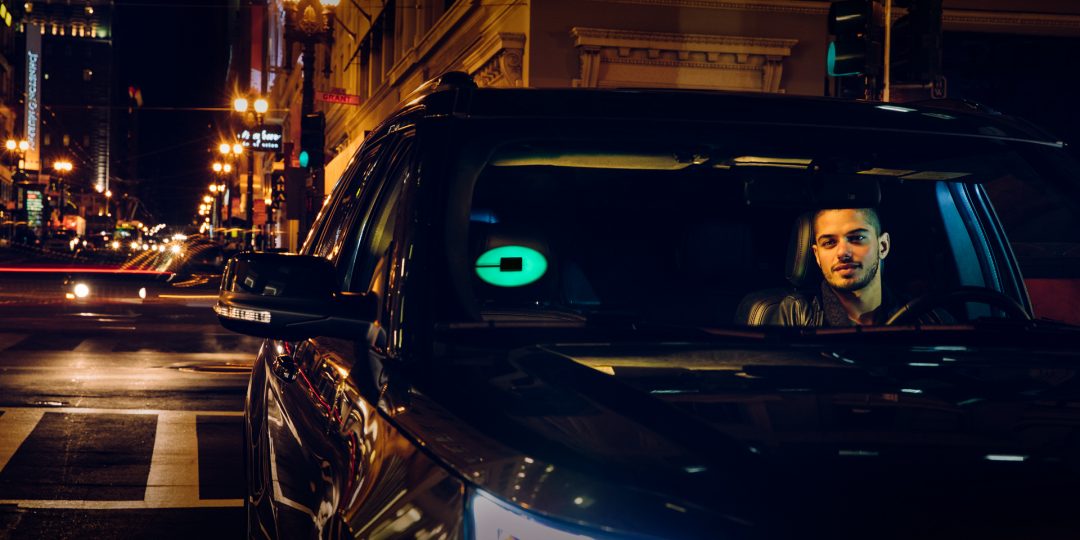 A driver at night with an Uber beacon shining in his car.