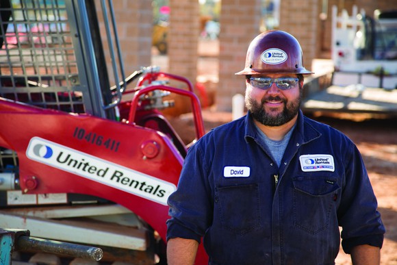 Person wearing hard hat next to a piece of equipment with United Rentals logo on it.