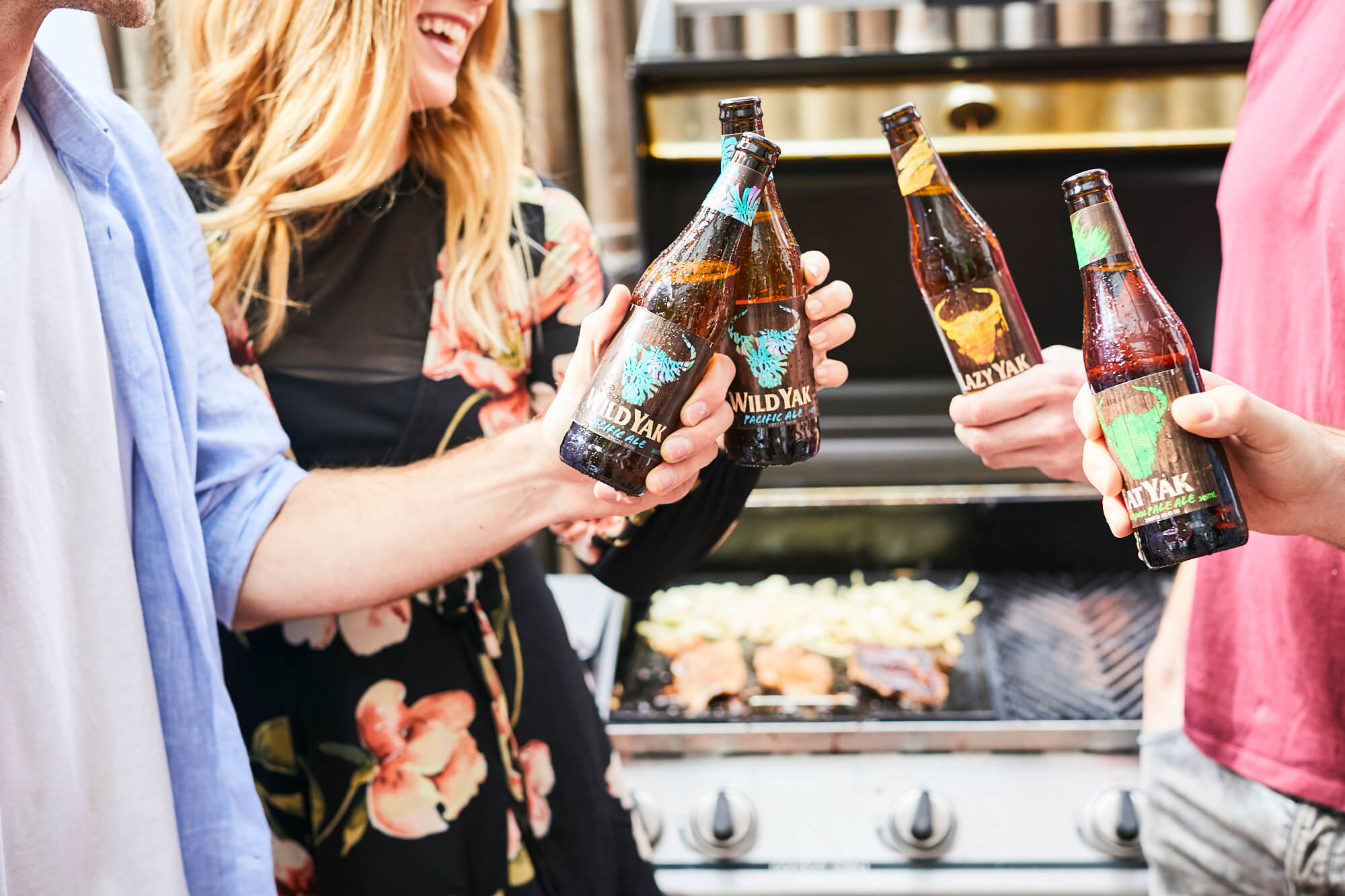 People holding bottles of Carlton & United Breweries Yak brand beer