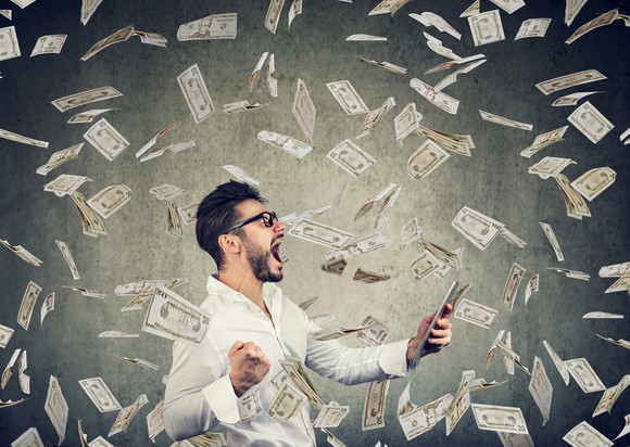 Man with tablet among swirling money