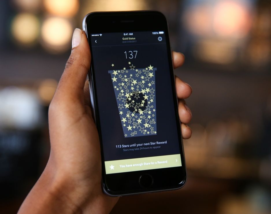 A person holds up a phone running the Starbucks app.