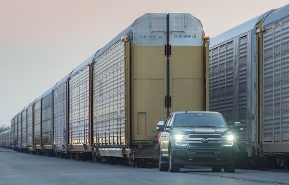 A prototype electric F-150 pickup, which looks like a standard 2019 model, is shown preparing to pull a line of double-decker rail cars.