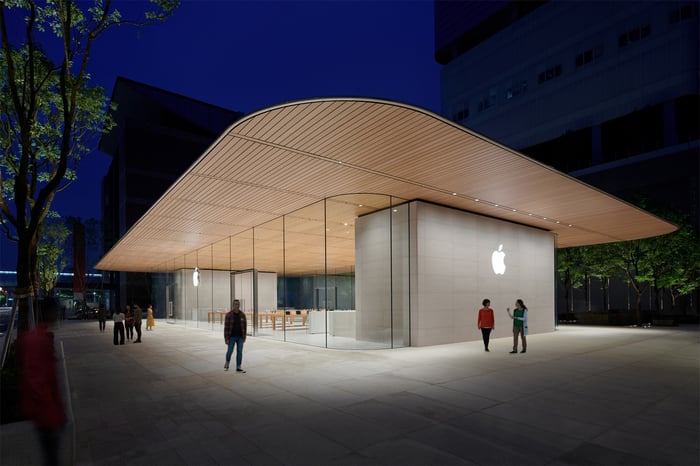 The new Apple store in Taipei with a wooden roof overextending the glass exterior and the white Apple logo displayed on the side of the building.
