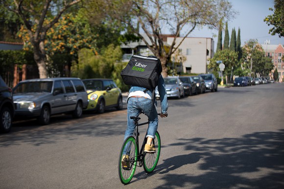 Man on a bike with an Uber Eats insulated carrier on his back