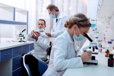Scientist lookin at slides through microscopes