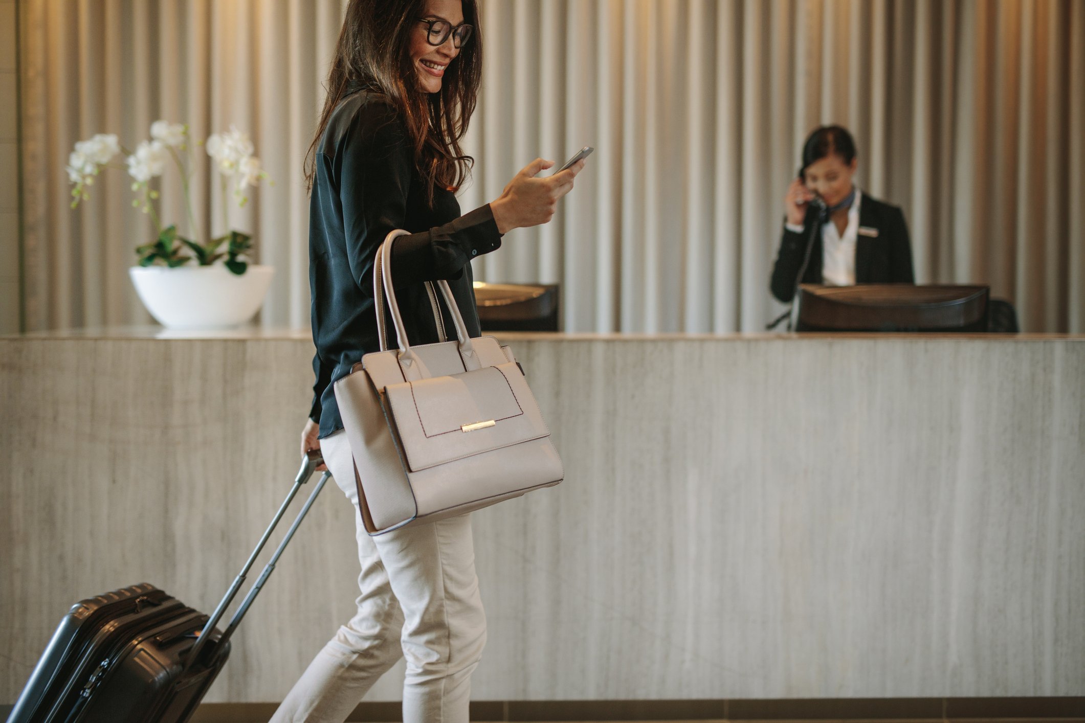 A business traveler checks her phone in a hotel lobby.